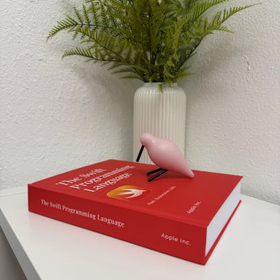 Photo of The Swift Programming Language as a physical print textbook. The cover is red. The book is lying flat against a level surface.