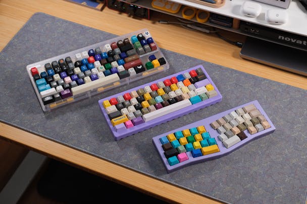 Three keyboards covered in a mish-mash of mismatched keycaps