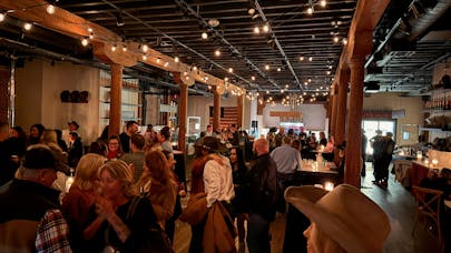 A lively crowd gathers inside the Country Club in Yountville under warm string lights