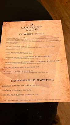 A printed paper menu for the Country Club displaying the Cowboy Bites and Homestyle Sweets food sections